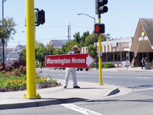 On Webster St., Man displaying sign showing the way to Bayport, Alameda, California, July 11, 2004     
